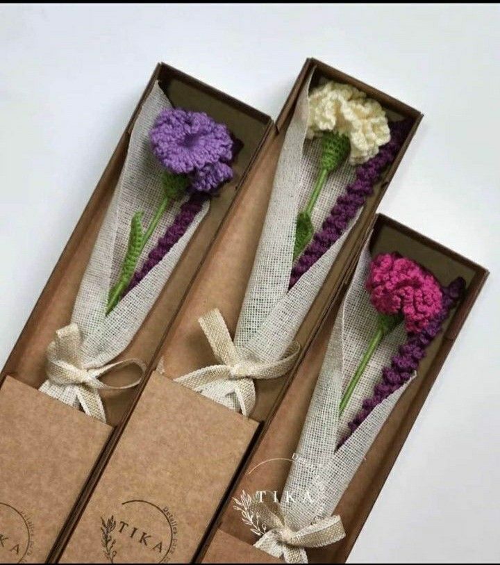 three boxes with flowers in them sitting on a table next to some string wrapped paper