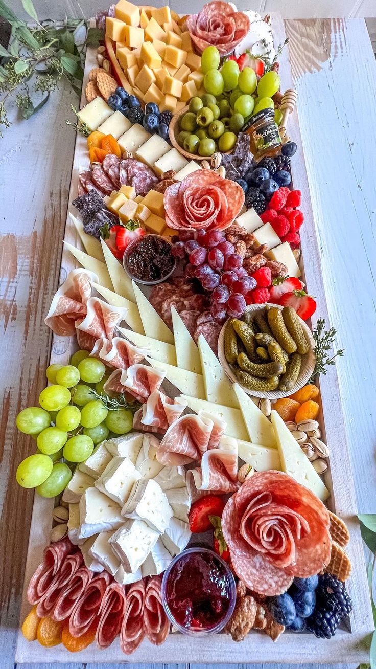 an assortment of cheeses, fruits and meats on a platter