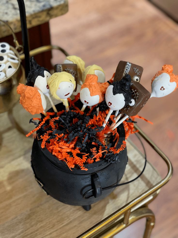 there are many halloween candies in the cupcake holder on the table with orange and black sprinkles