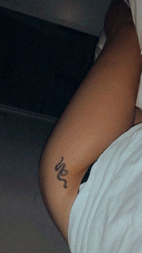 a person with a snake tattoo on their arm and stomach, laying down in bed