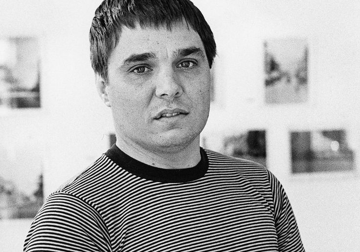 black and white photograph of a man in striped shirt looking at the camera with serious look on his face