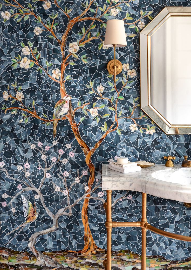 a bathroom with blue mosaic tiles and a tree wallpapered in gold, white and pink