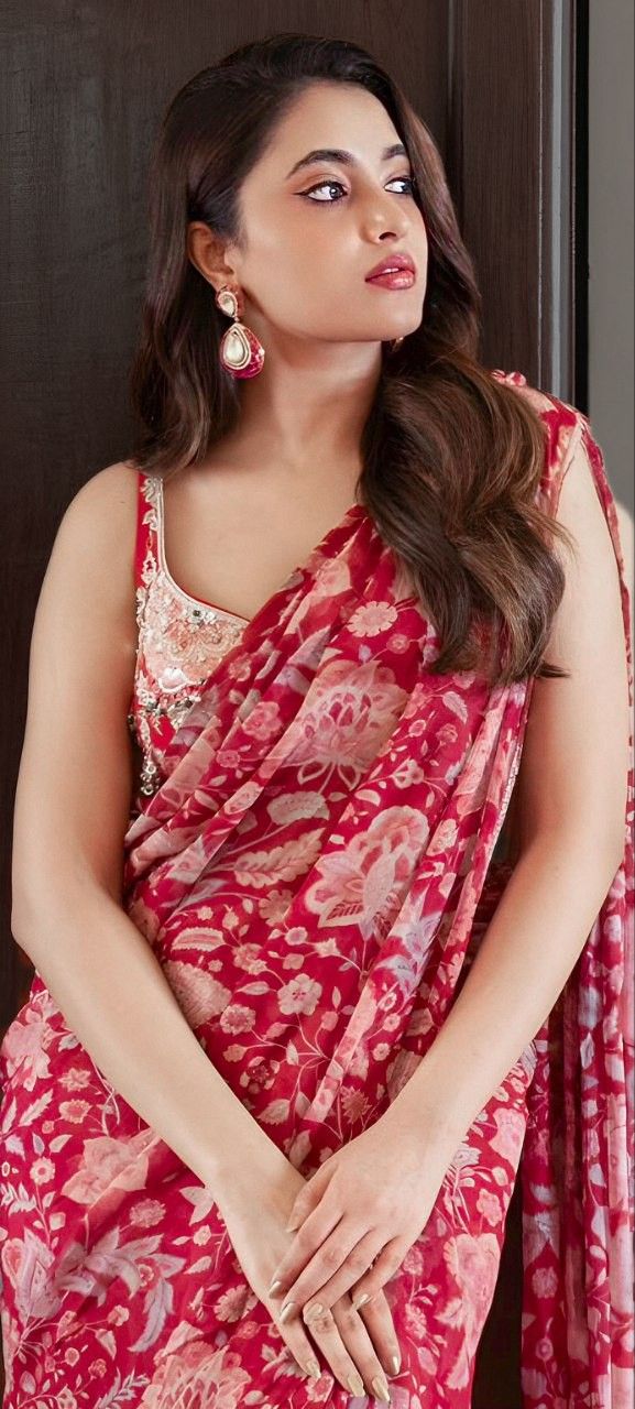 a woman in a red sari posing for the camera with her hands on her hips