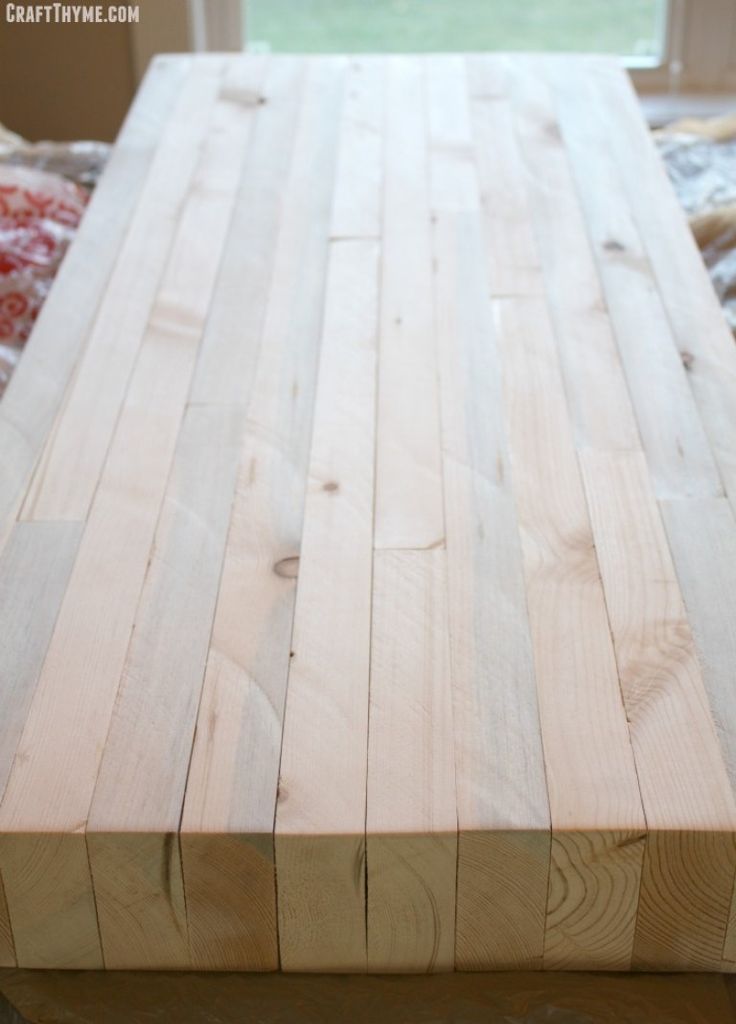 a table made out of wood sitting on top of a wooden floor next to a window