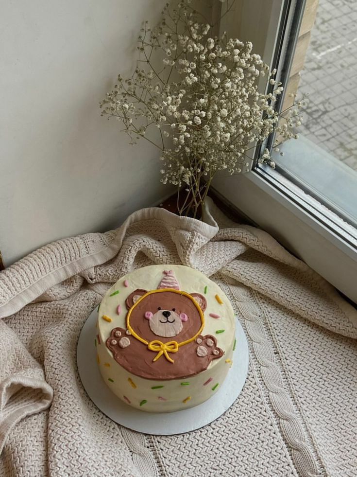 a decorated cake sitting on top of a white plate next to a window sill