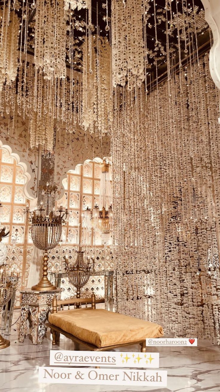 an ornate chandelier hangs from the ceiling above a bench in front of large windows