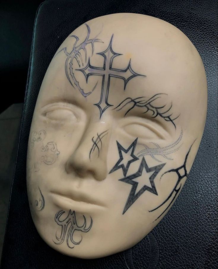 a white mask with crosses and stars painted on it's face is sitting in a chair