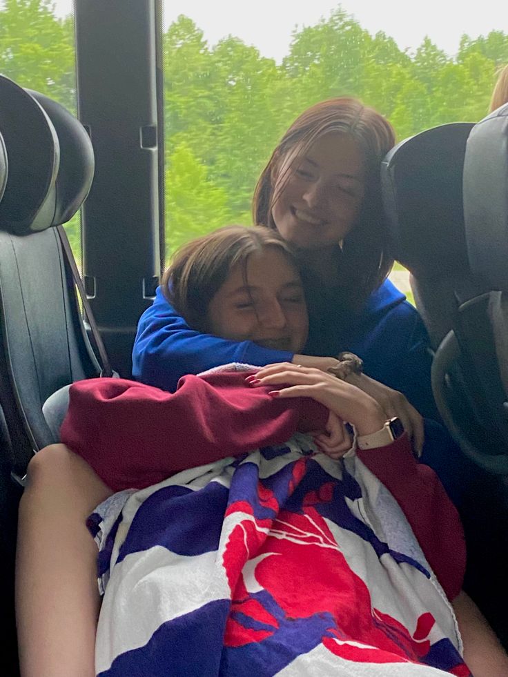 two women hugging each other on a bus