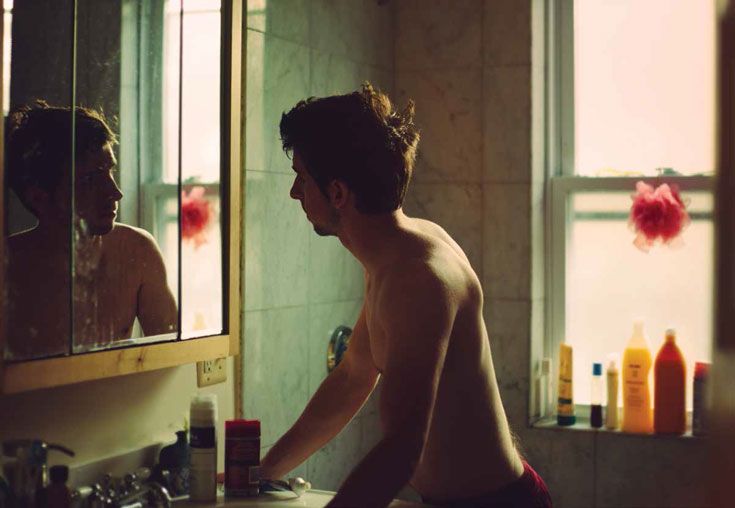 a shirtless man standing in front of a bathroom mirror looking at himself in the mirror