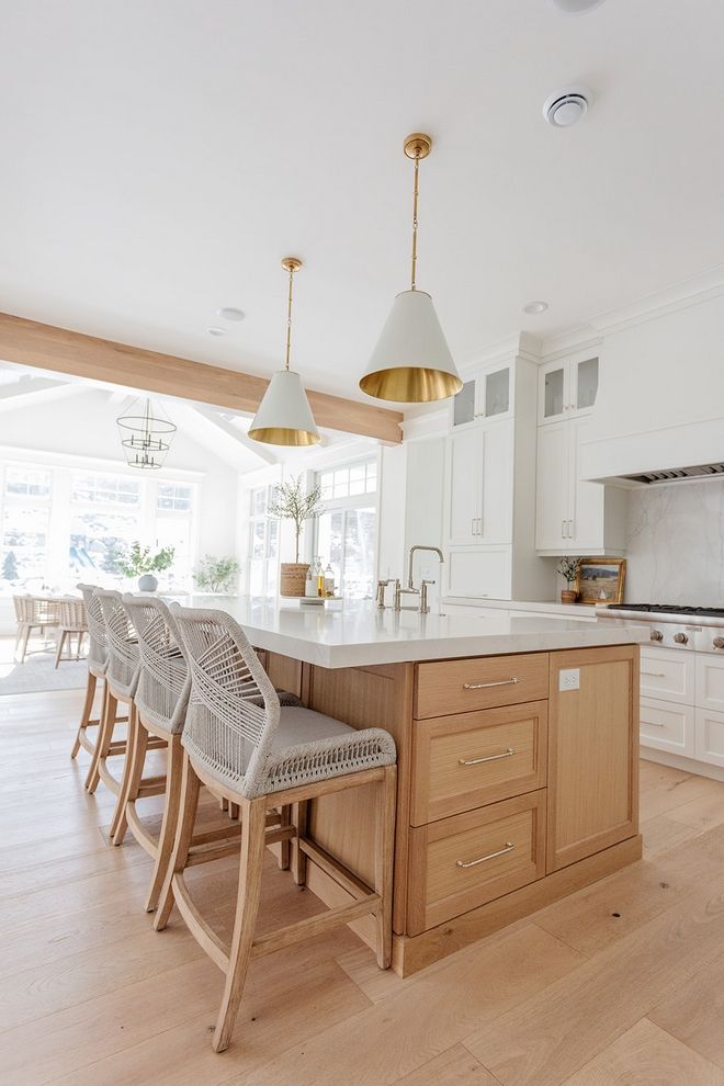 a large kitchen with white cabinets and wooden flooring, along with bar stools