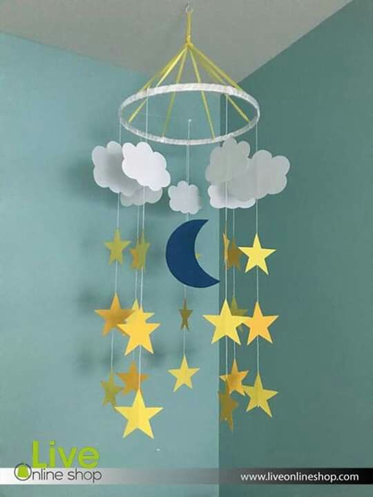 a mobile with stars and clouds hanging from it's sides in a room next to a blue wall