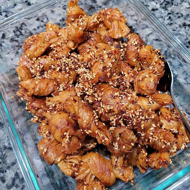 a glass dish filled with chicken wings covered in sesame seeds