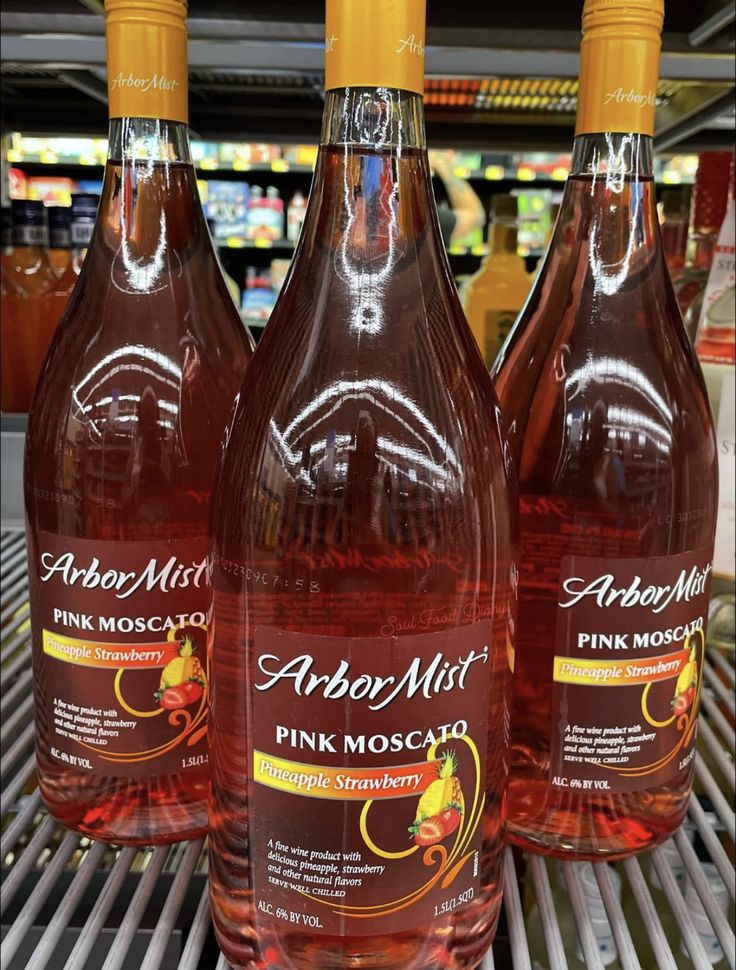 three bottles of pink moscarella on a rack in a grocery store, with the label above them