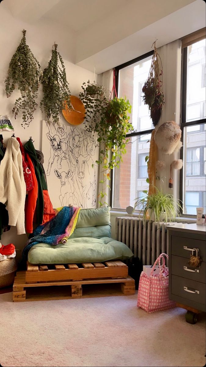 a room filled with lots of hanging plants and clothes on the rack next to a window