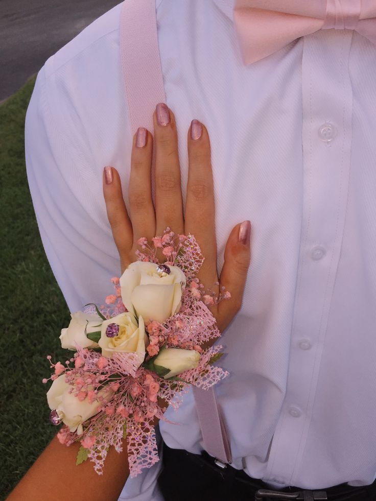 a person wearing a white shirt and pink tie holding a bouquet of flowers in their hands