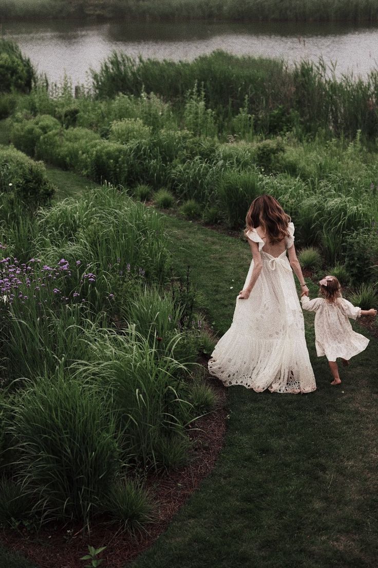 a mother and her daughter walking in the grass