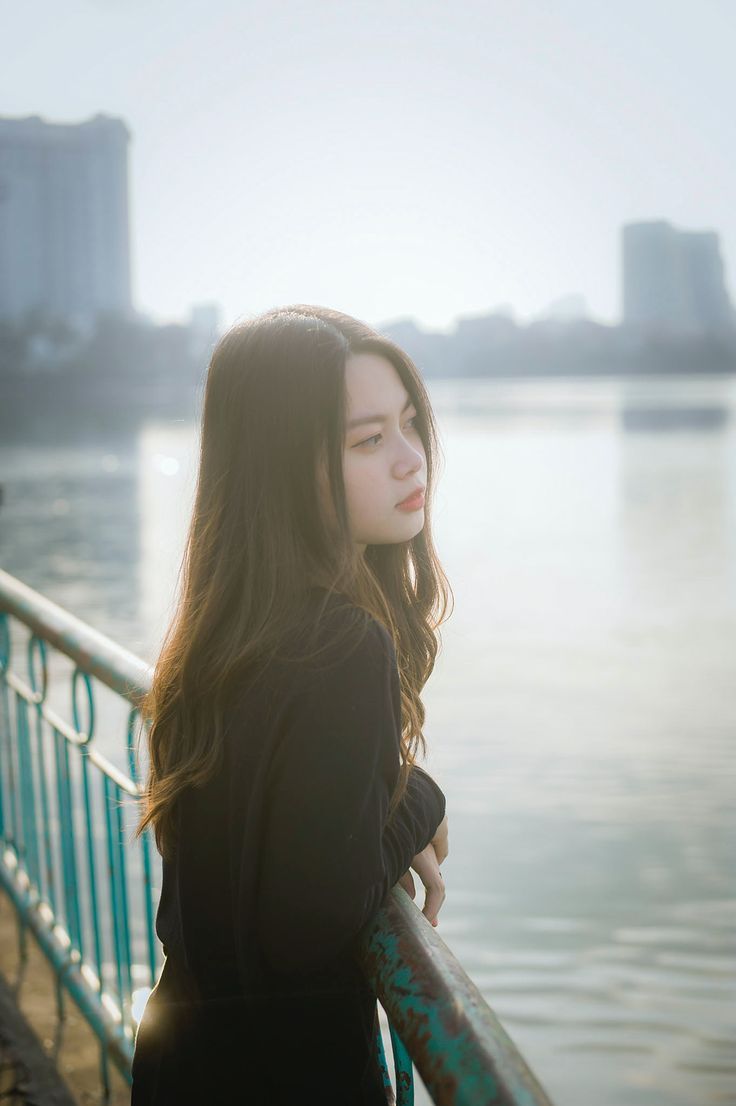 a woman standing next to a railing near the water