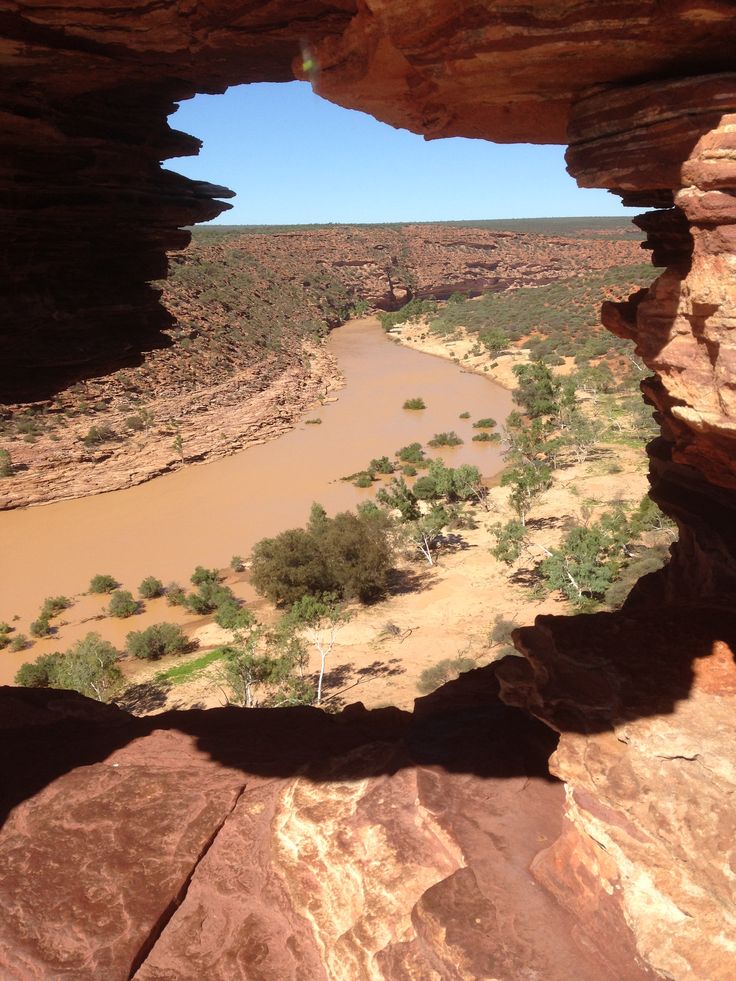 the view from inside a cave looking down at a river