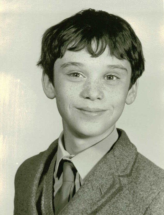 a black and white photo of a young boy in a suit smiling at the camera