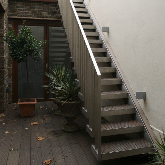 a set of stairs leading up to a patio with potted plants on the side