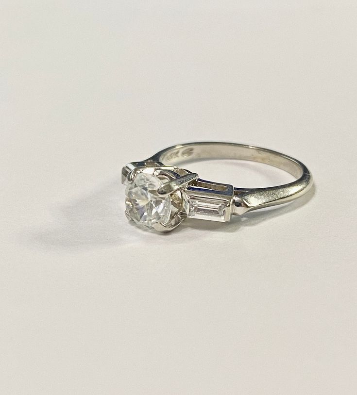 Beautiful vintage 14k white gold ring featuring a genuine topaz gem with beautiful Spinel Baguette shoulders! The topaz gemstone's estimated weight is .84 cts. It is round cut, faceted, and secured in a raised four prong setting with 2 spinel gemstones on each side with an Estimated .14 cts each.The Art Deco setting is stunning, with raised spinel shoulder designs trailing down the ring. ERA - Circa 1970s, METAL / MATERIAL - 14k White gold, 1 genuine topaz (estimated .84 carats) 2 Spinel gemston Classic Emerald Cut Topaz Ring With Vs Clarity, Vintage White Gia Certified Rings, Classic 14k White Gold Emerald-cut Topaz Ring, Classic 14k White Gold Emerald Cut Topaz Ring, Classic Emerald-cut Topaz Ring For Wedding, Classic Emerald Cut Topaz Ring For Wedding, Classic Emerald Cut Topaz Wedding Ring, Vintage White Emerald Cut Ring, Vintage White Asscher Cut Rings