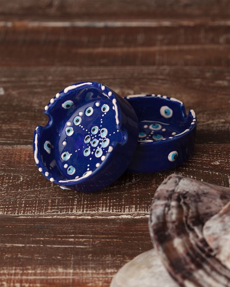 two blue bowls sitting on top of a wooden table next to seashells and shells