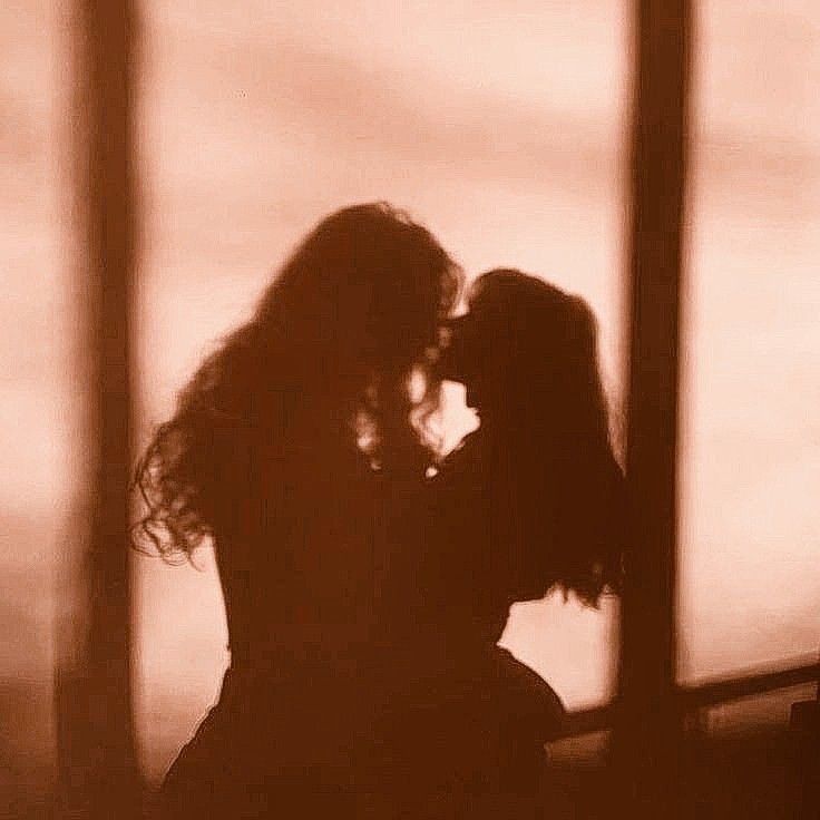 the silhouette of two people kissing in front of a window with their arms around each other