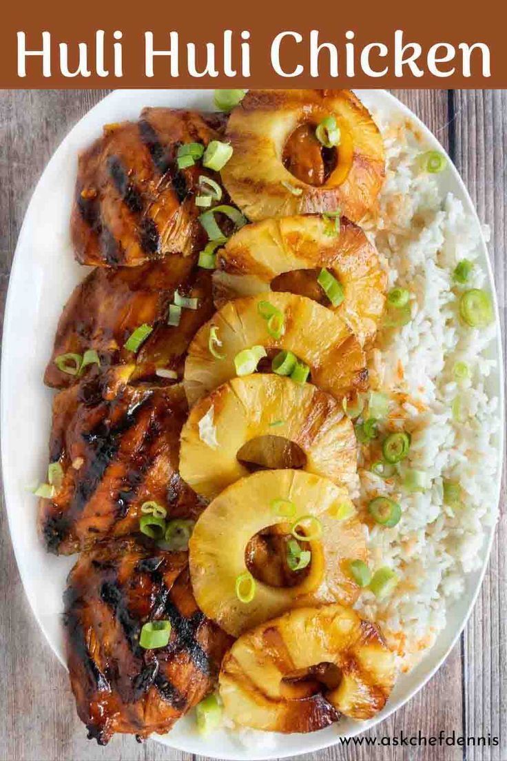 a white plate topped with chicken and pineapples next to rice on a wooden table