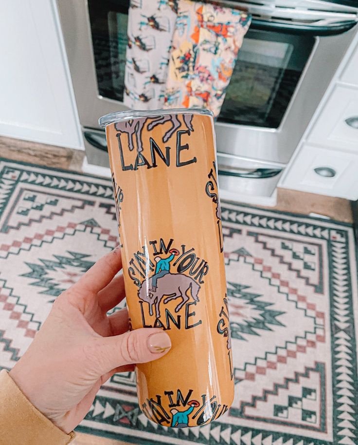 a person holding up a cup in front of a stove top oven with the word lake printed on it