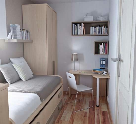 a small bedroom with a bed, desk and bookshelf in the corner by the door