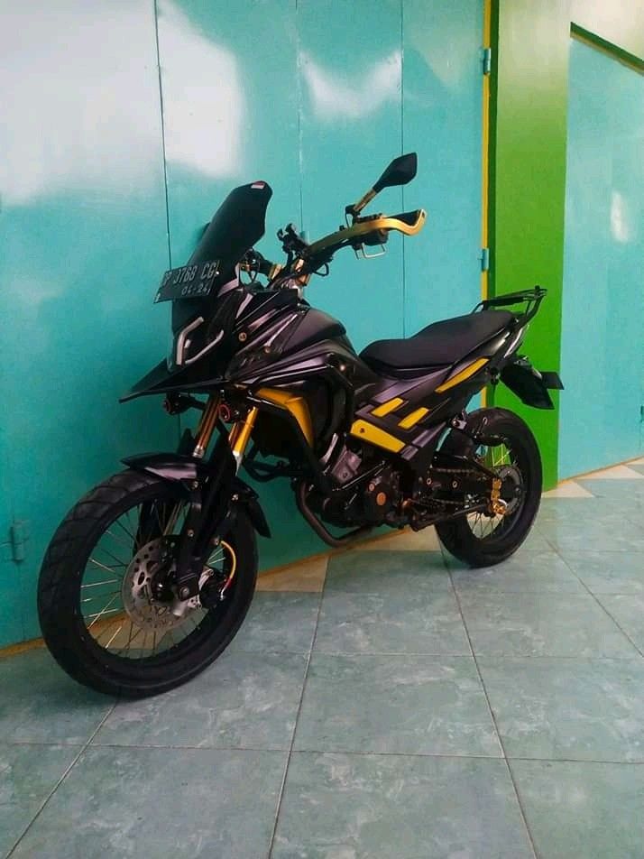 a black and yellow motorcycle parked in front of a blue wall next to a green door