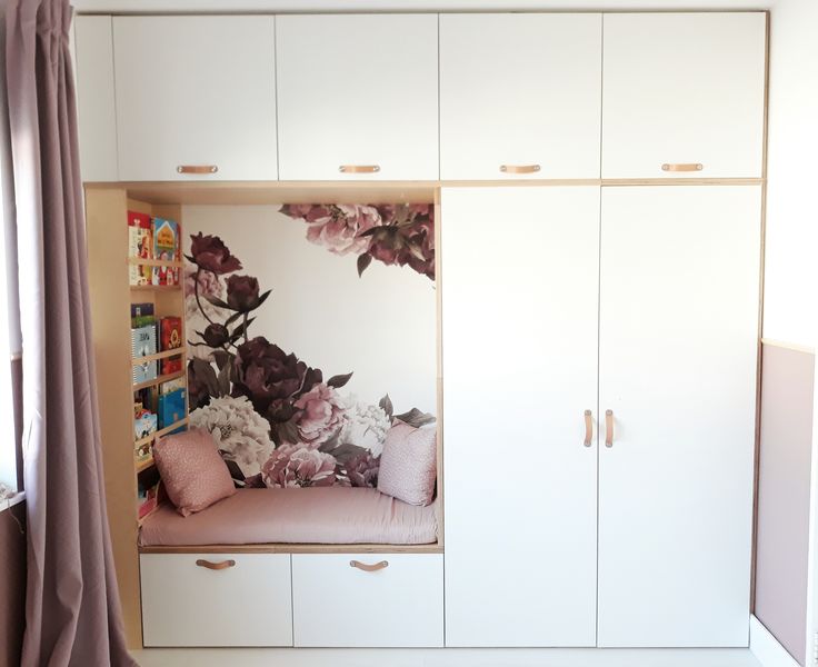 a bedroom with white cupboards and flowers on the wall