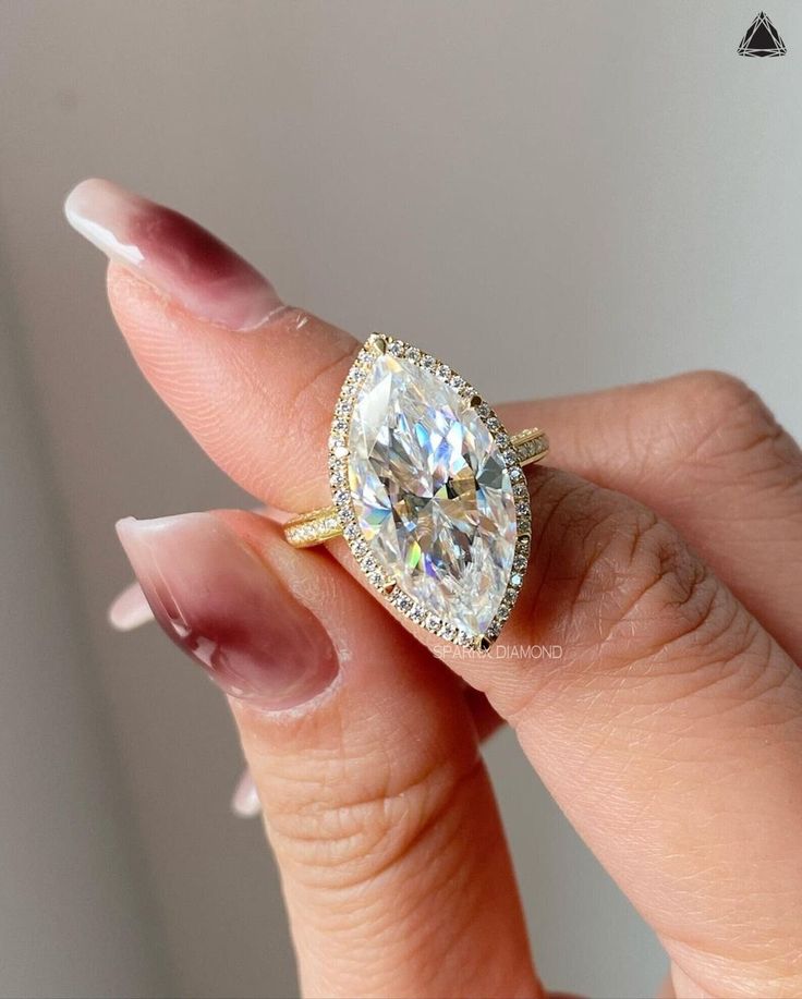 a woman's hand holding an oval shaped diamond ring