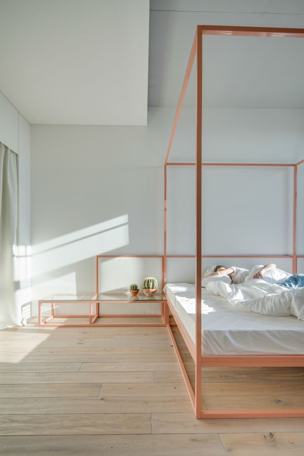 an orange bed frame in a bedroom with white walls and wood floors, along with a wooden floor