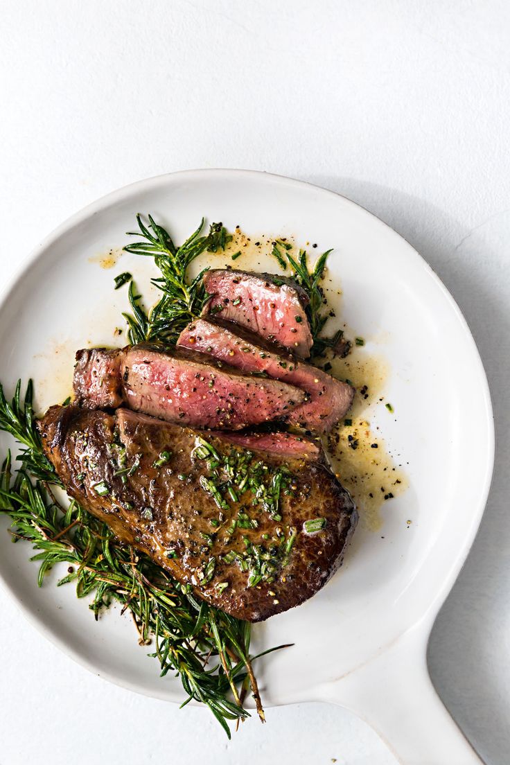 steak with herbs and seasoning on a white plate