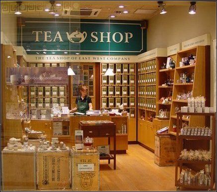 a store front with the words tea shop on it's glass door and shelves full of items