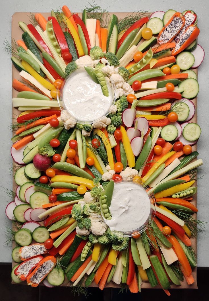 a platter filled with assorted veggies and dip in the middle on top of it