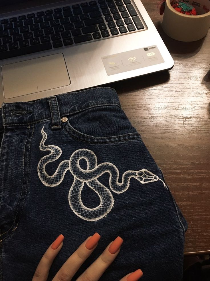 a woman's hand on the back of her jean pants with a snake embroidered on it