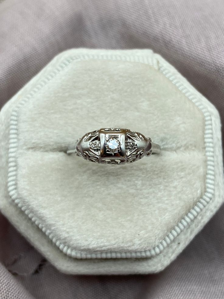 an antique diamond ring sits in a velvet box on top of a cloth covered surface