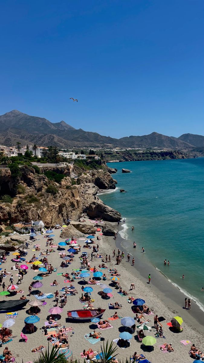 many people are on the beach with umbrellas