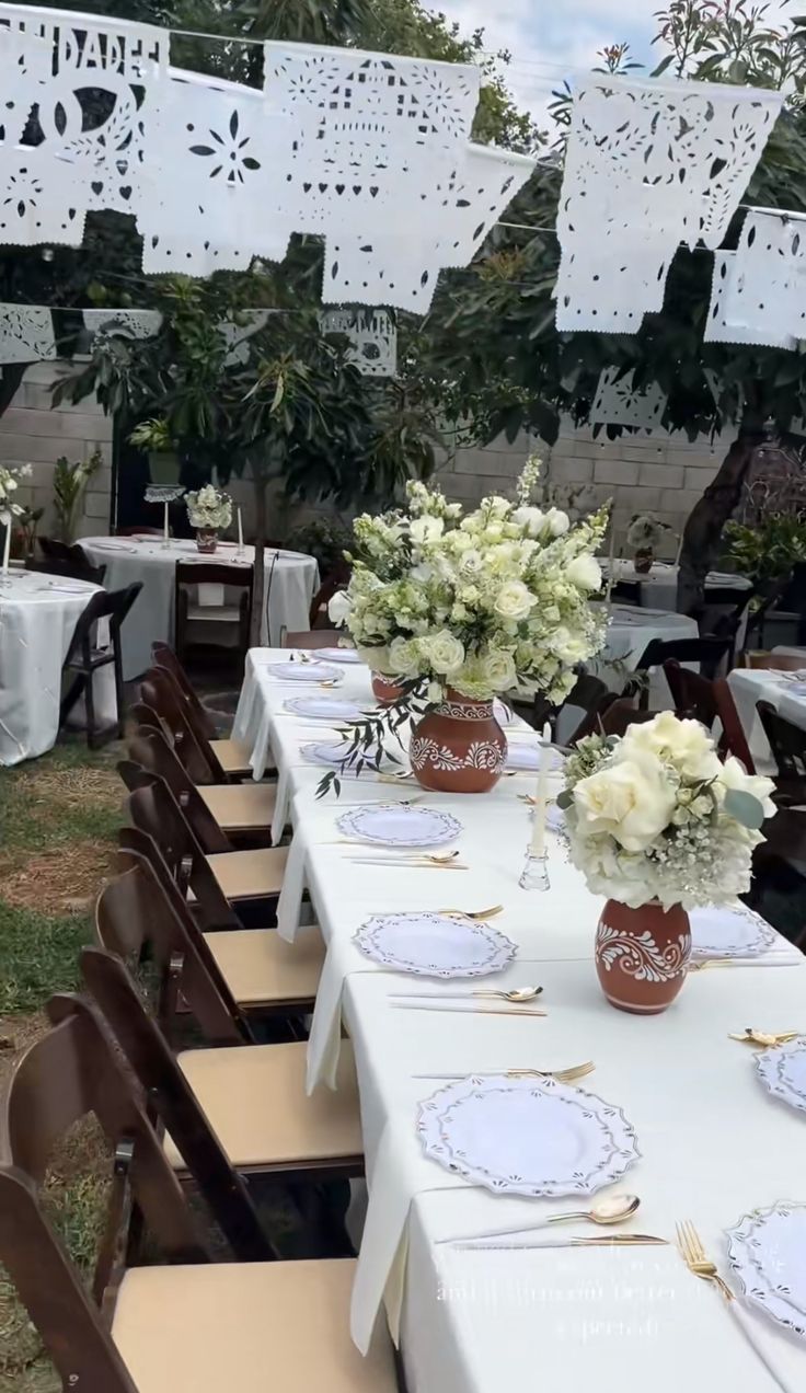 tables set up with white table cloths and place settings for an outdoor wedding reception