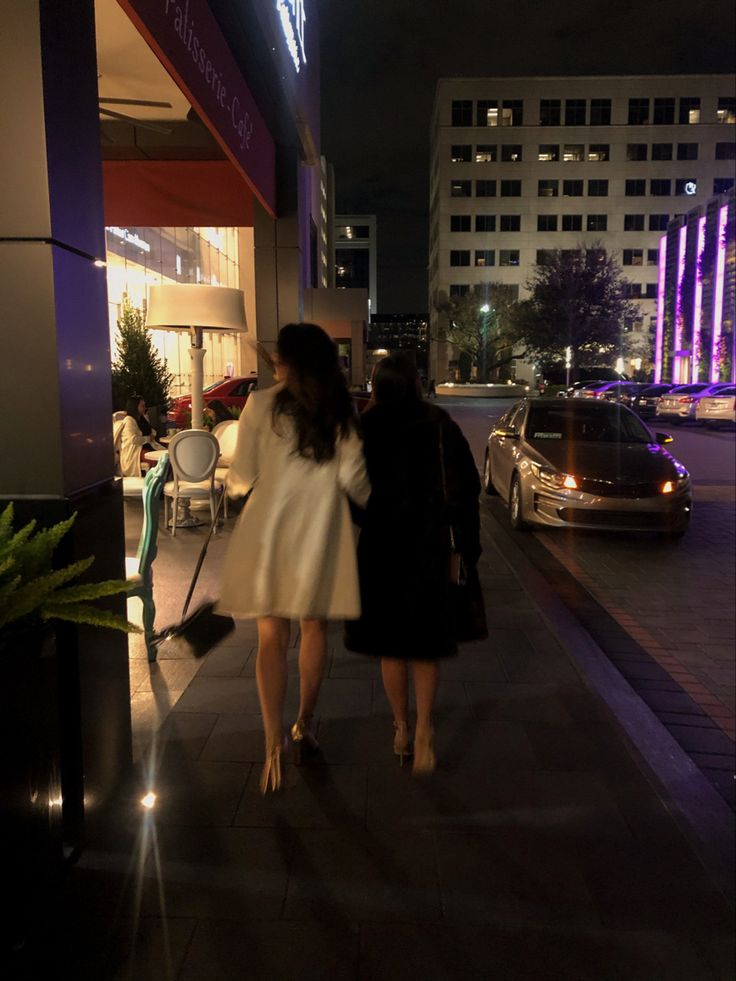 two women walking down the sidewalk at night