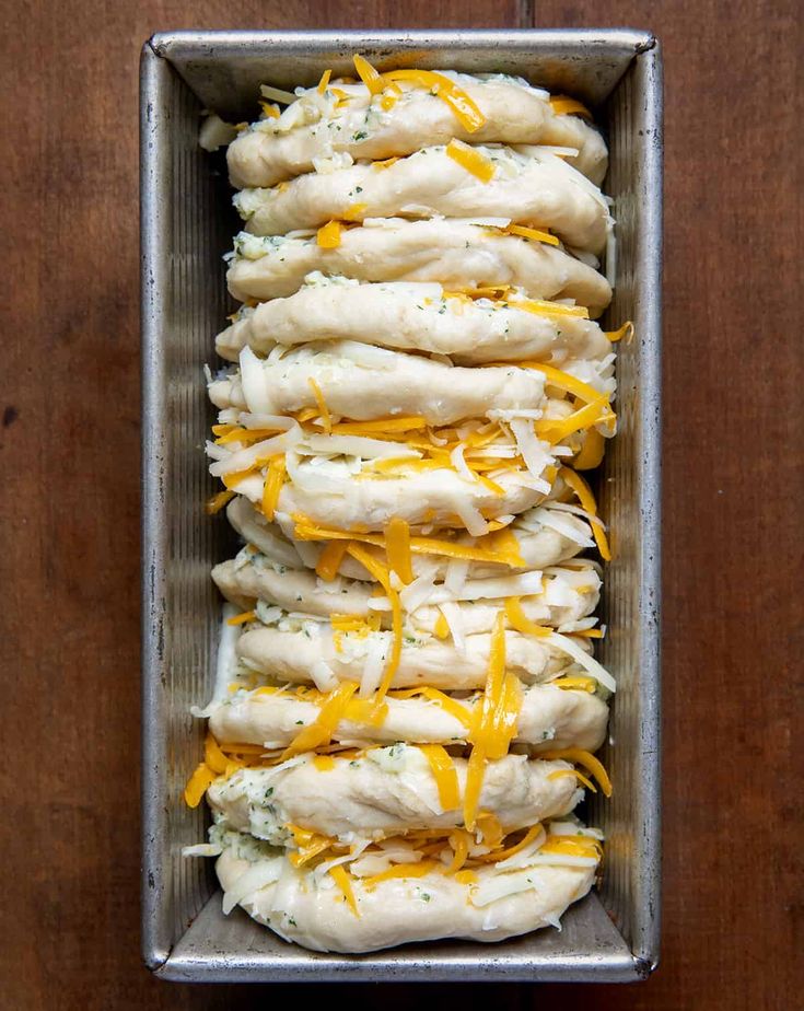 a metal pan filled with dumplings covered in cheese