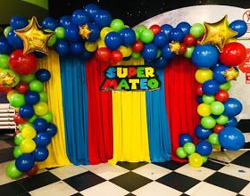 an arch made out of balloons and streamers in front of a checkered floor