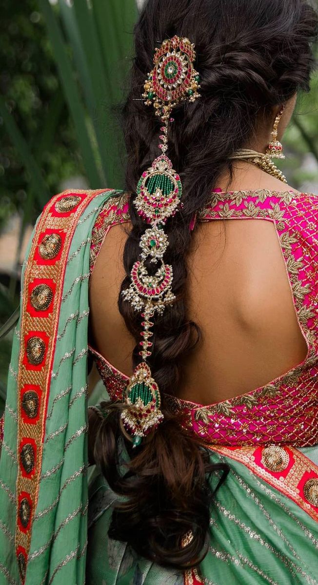 the back of a woman's head wearing a green and red sari with jewels on it