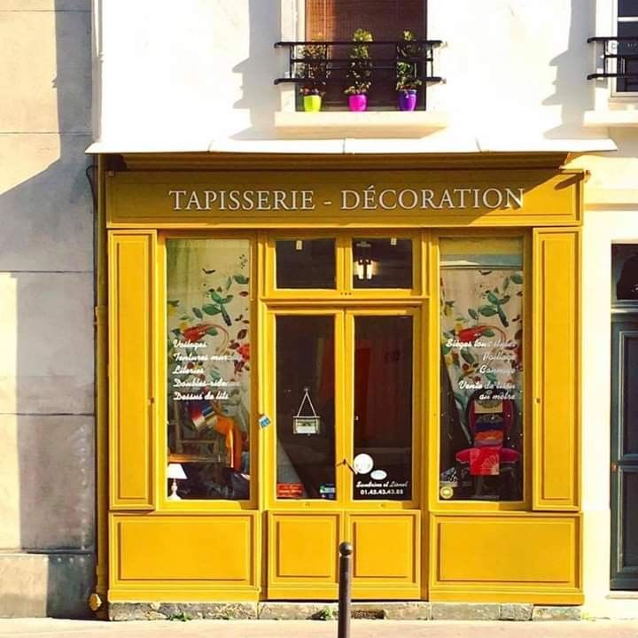 a store front with yellow doors and windows on the side of the street in paris