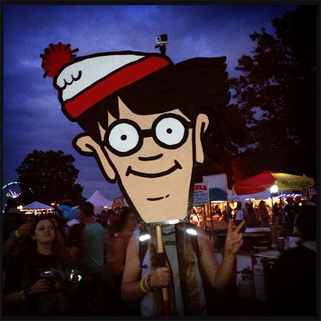 a man with glasses and a hat on his head at an outdoor event in the evening