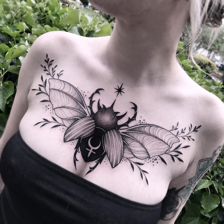 a woman's chest with a black and white bee tattoo on her left shoulder