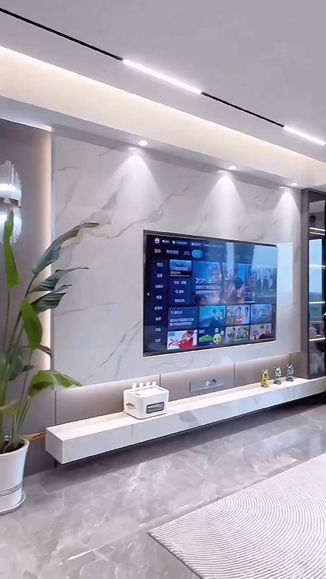 a large flat screen tv mounted on the wall in a living room next to a plant