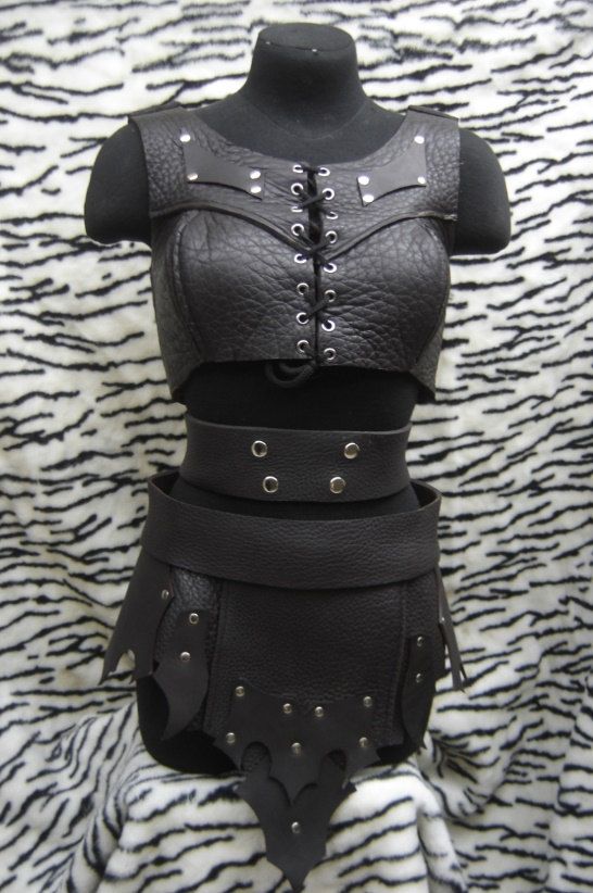 a woman's black leather bra and skirt with metal rivets on it